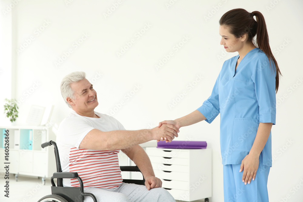 Obraz premium Senior disabled man with young orthopedist in rehabilitation clinic