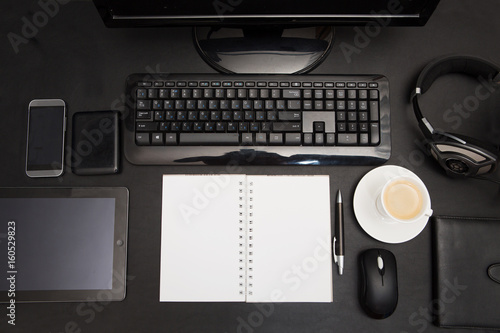 Office leather desk table with notepad, coffee cup, computer, smartphone and headphones. Top view. 
