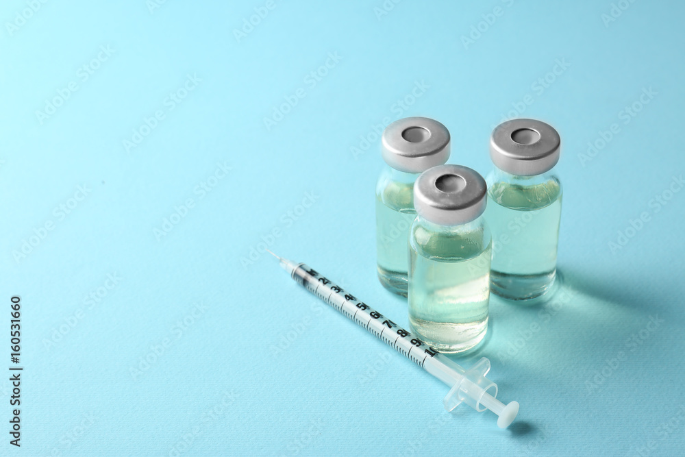 Vaccine in vials with syringe on color background Vaccine in vials with syringe on color background