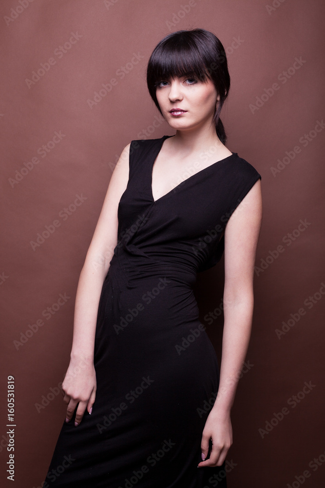 Woman in long black dress on brown background in studio photo. Beauty and fashion. Model test Woman in long black dress on brown background in studio photo. Beauty and fashion. Model test