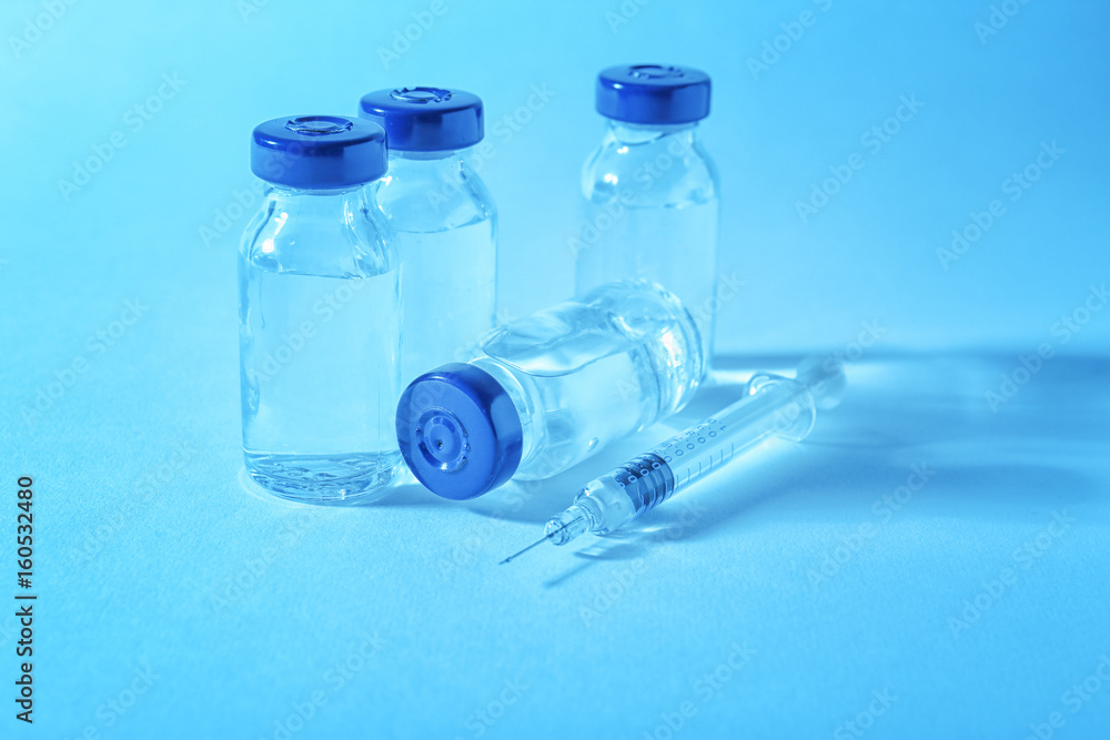 Vaccine in vials with syringe on color background Vaccine in vials with syringe on color background