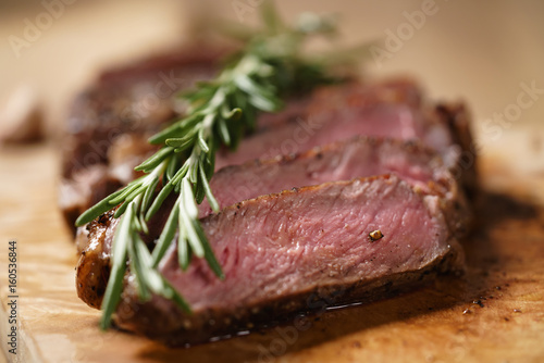 sliced medium rib eye steak with rosemary branch