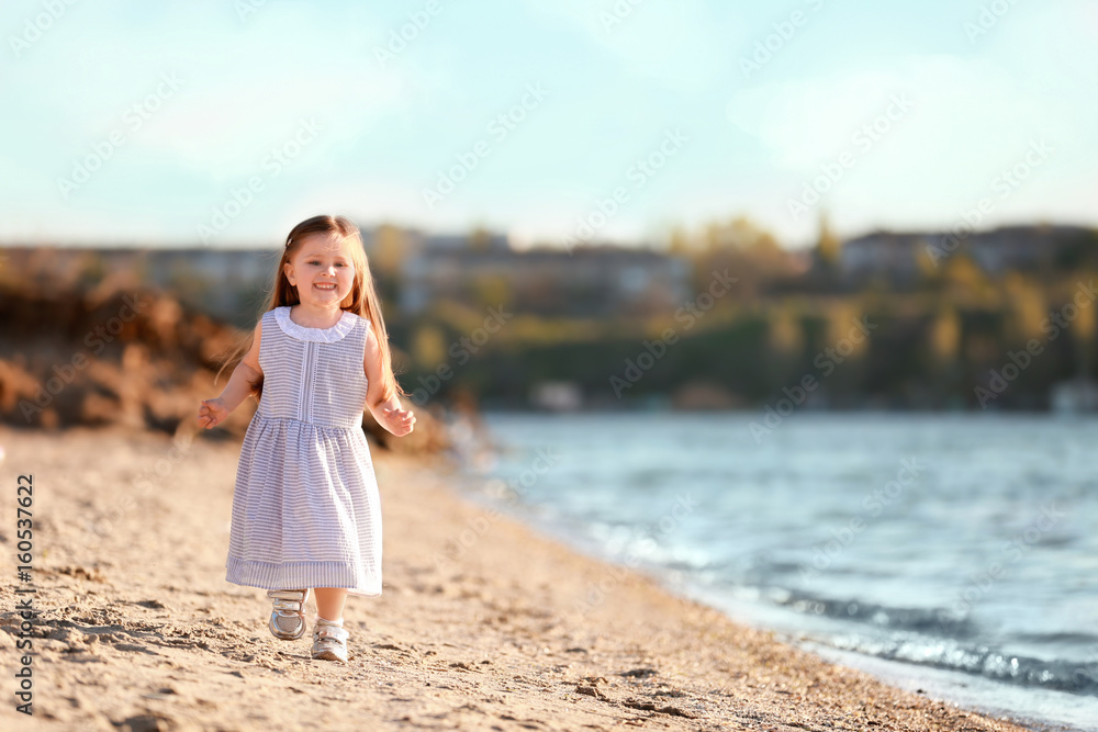 Cute little girl running along river bank on spring day Cute little girl running along river bank on spring day