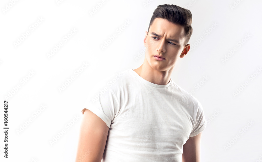 Fototapeta premium Fashion portrait of a handsome serious man with trendy hairstyle in a white shirt