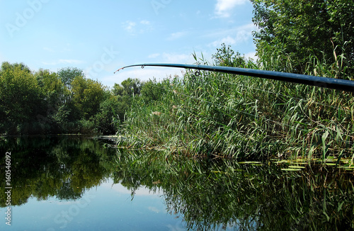 Fishing rod on the background of smooth water surface at noon. photo