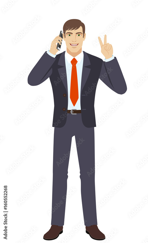 Businessman talking on the mobile phone and showing victory sign