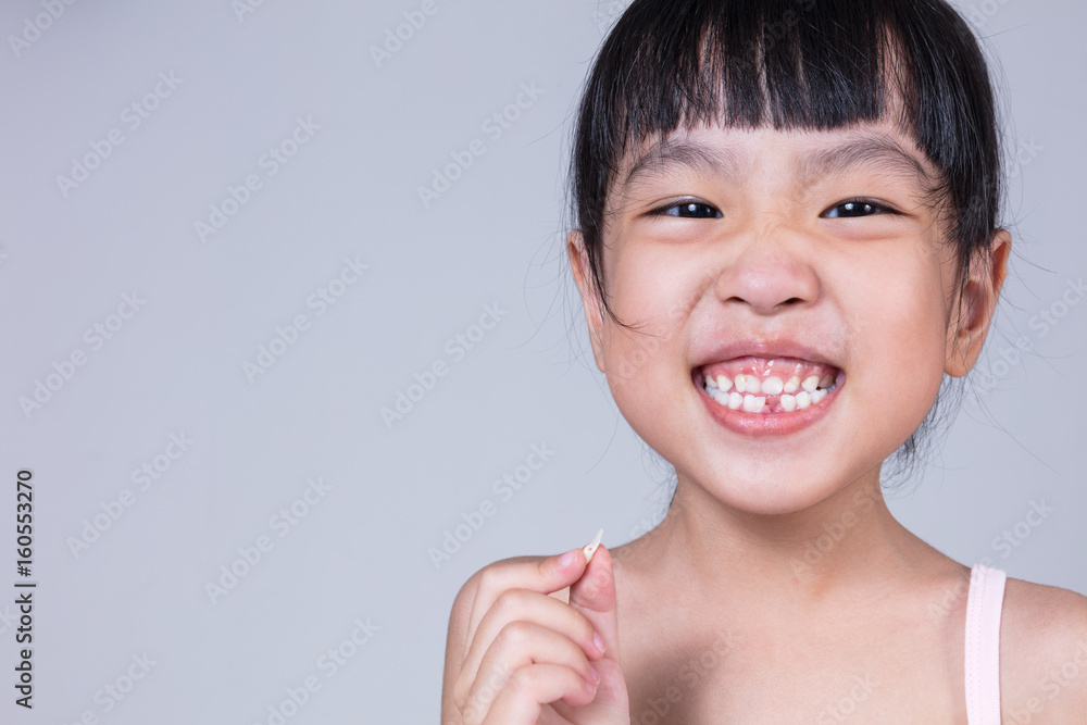 Asian Chinese little girl holding her missing tooth Asian Chinese little girl holding her missing tooth