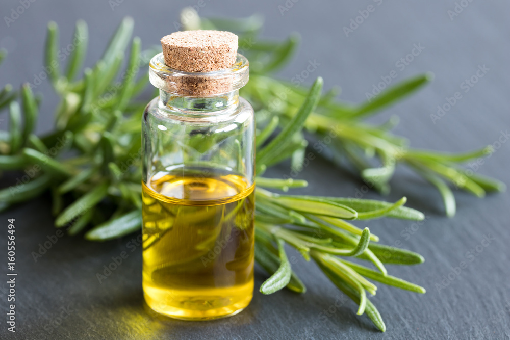 A bottle of essential oil with fresh rosemary twigs A bottle of essential oil with fresh rosemary twigs
