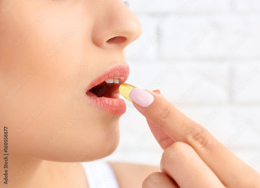 Woman taking fish oil pill, closeup Woman taking fish oil pill, closeup