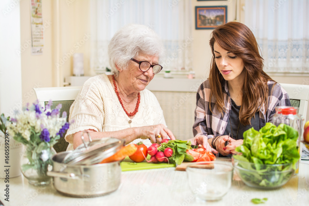 Grandmother and granddaughter preparing food together at kitchen. Grandmother and granddaughter preparing food together at kitchen.