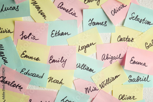 Closeup of paper stickers with different names on white wall. Concept of choosing baby name photo