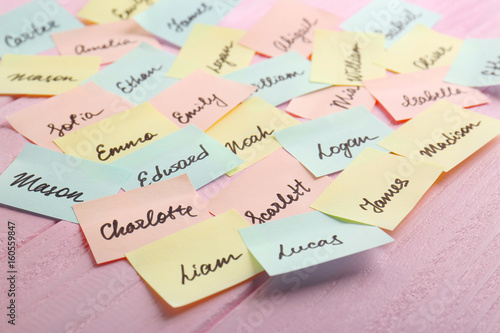 Paper stickers with different names on wooden background. Concept of choosing baby name