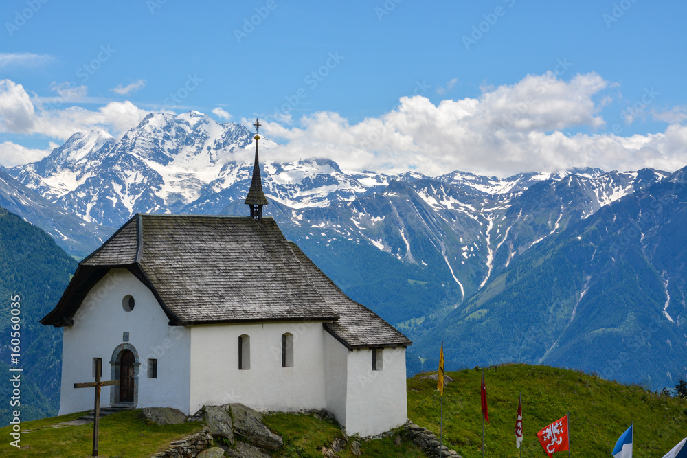 An old white chapel with the mountains in the background An old white chapel with the mountains in the background