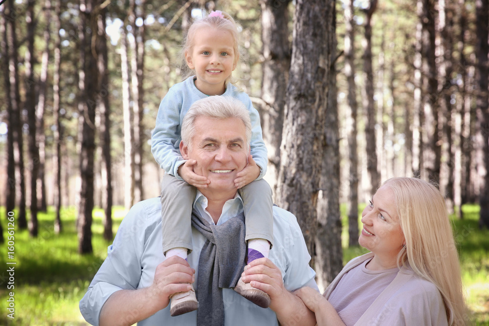 Happy senior couple with granddaughter in forest on sunny day Happy senior couple with granddaughter in forest on sunny day