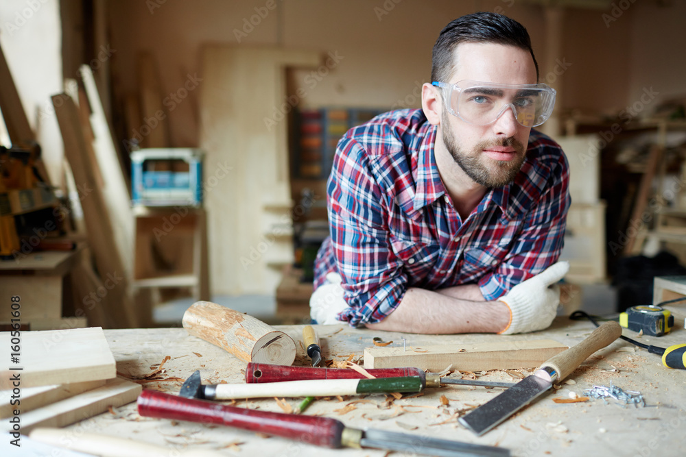 Carpenter in protective eyeglasses in his workshop Carpenter in protective eyeglasses in his workshop