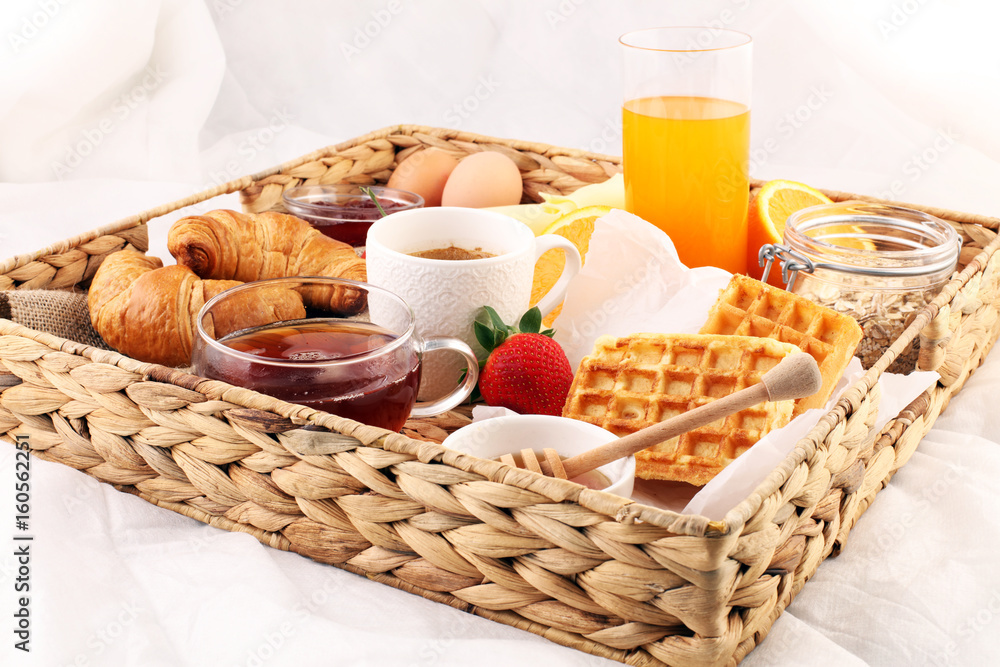 breakfast in bed with fruits and pastries on a tray -waffles, croissants, coffe and juice breakfast in bed with fruits and pastries on a tray -waffles, croissants, coffe and juice