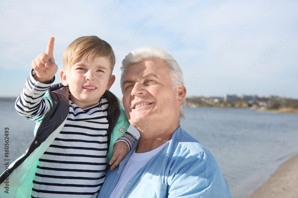Happy grandfather with little boy on river bank Happy grandfather with little boy on river bank