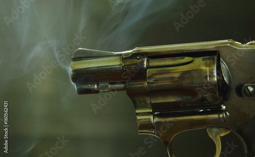 Fotografie, Obraz revolver gun with smoke floating in the air after shoot on black background