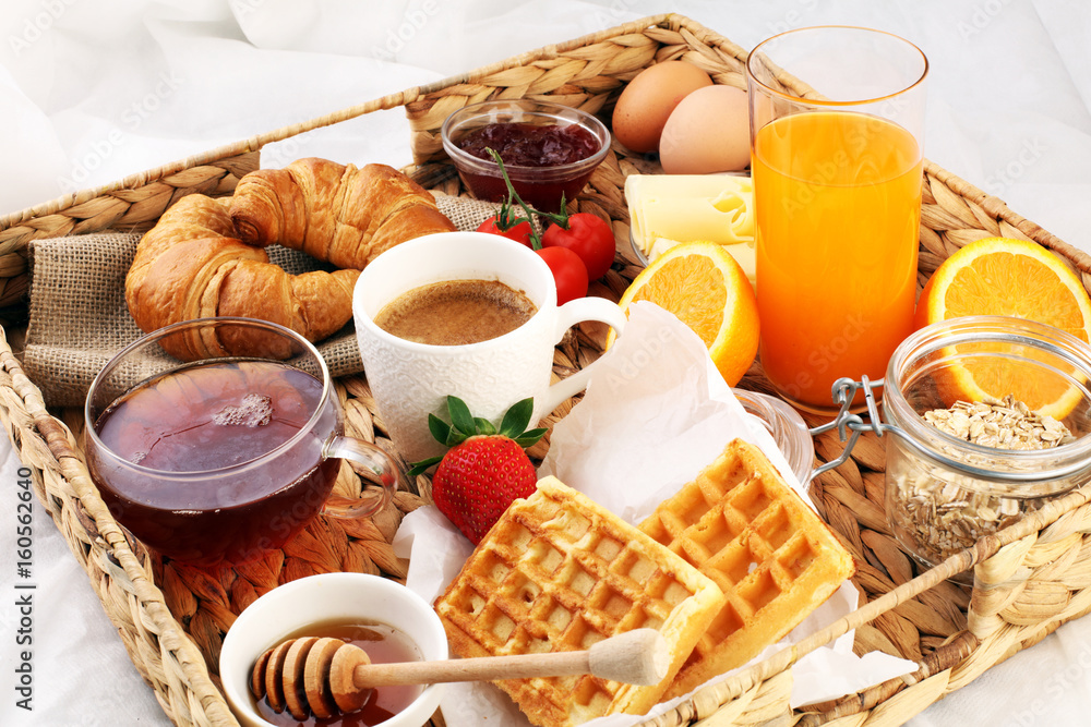 breakfast in bed with fruits and pastries on a tray -waffles, croissants, coffe and juice breakfast in bed with fruits and pastries on a tray -waffles, croissants, coffe and juice