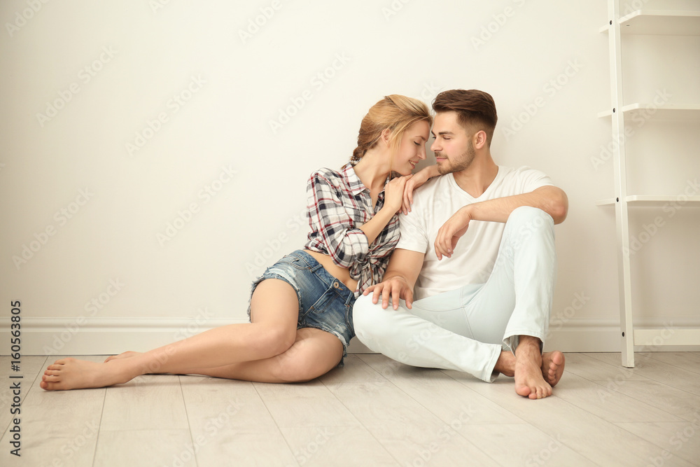 Happy young couple sitting on floor at home Happy young couple sitting on floor at home