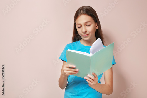 Cute pretty girl with book on color background