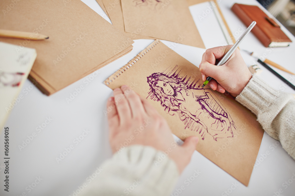 Man drawing young woman on page of notepad Man drawing young woman on page of notepad