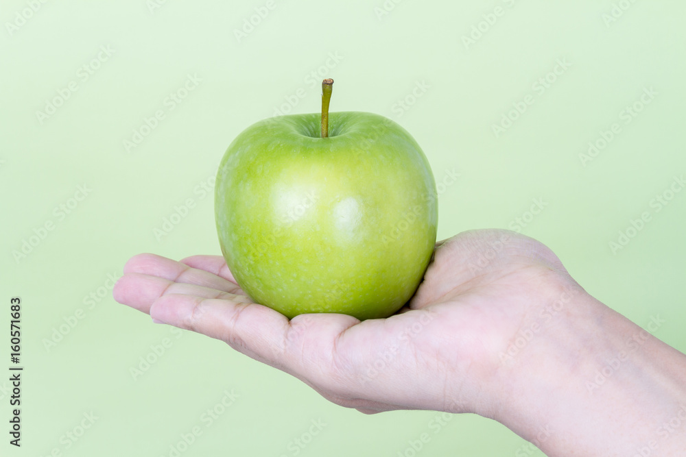 Hand holding fresh green apple on green background Hand holding fresh green apple on green background