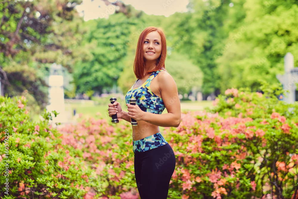 Portrait of redhead fitness female holds dumbbells. Portrait of redhead fitness female holds dumbbells.