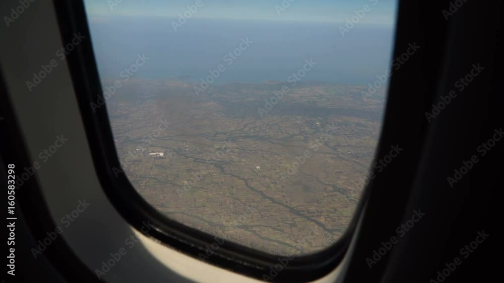 View through an airplane window on the tropical island, ocean, sky and clouds. Aerial view sea, clouds and sky as seen through window of an aircraft. 4K video. Aerial footage. Travel concept. View through an airplane window on the tropical island, ocean, sky and clouds. Aerial view sea, clouds and sky as seen through window of an aircraft. 4K video. Aerial footage. Travel concept.