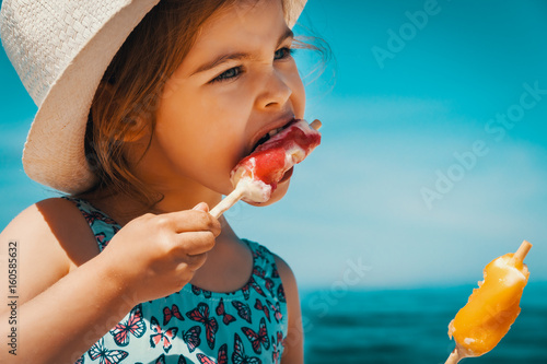 Obraz na płótnie Little and cute girl eating ice cream on the beach on vacation w salonie