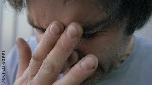 A man pinching his nose while experiencing pain.