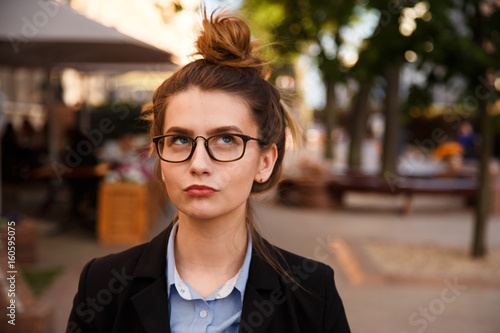 Fotografia Portrait of young woman in glasses is pondering outdoor.