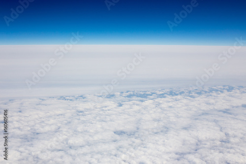 Above view of white clouds and a horizon with a blue sky.