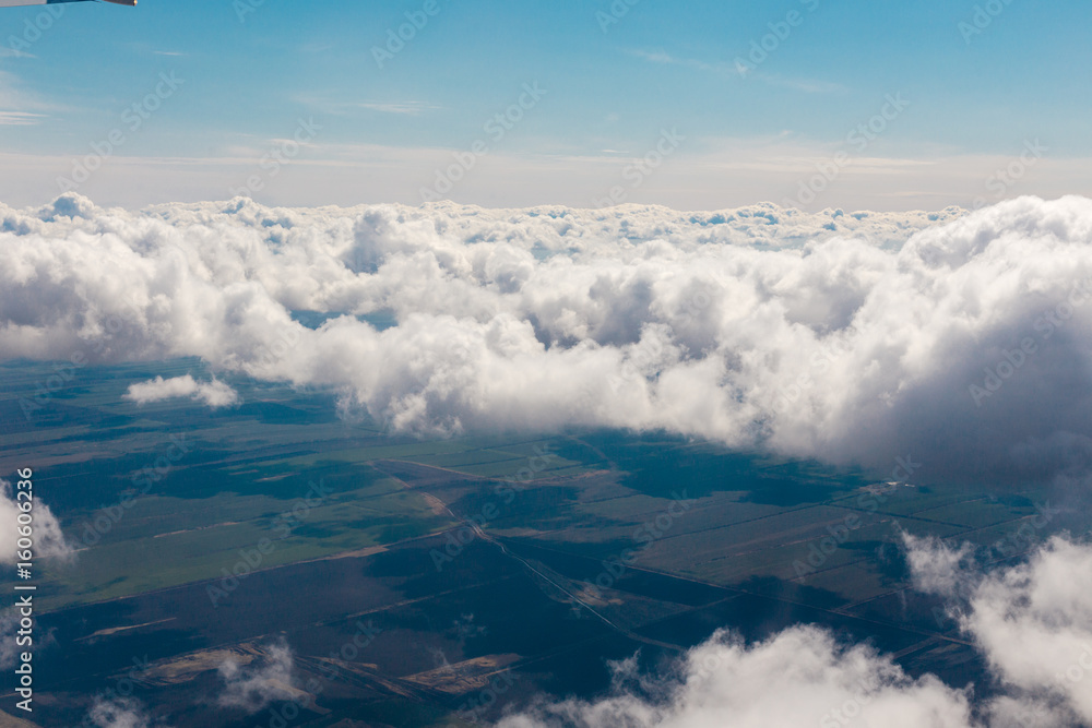 Fototapeta premium Above view of white clouds and lands with fields.