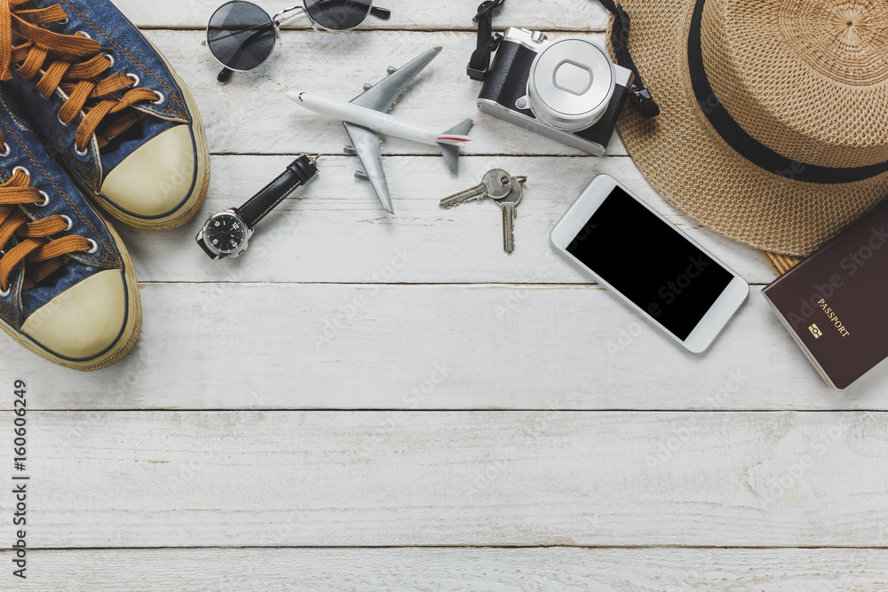Top view women accessories to travel concept.White mobile phone,airplane,hat,passport,watch,sunglasses on wood table.