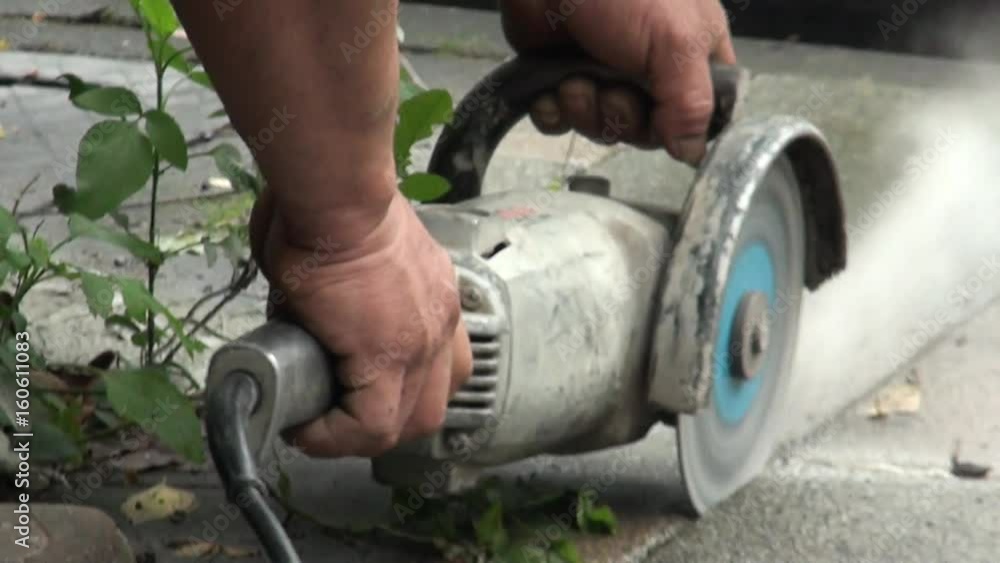 A bricklayer is using the angle grinder for cutting the flagstones on a