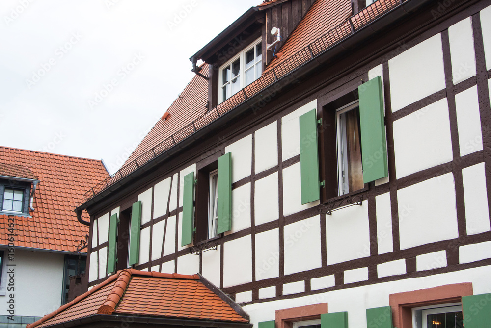 Traditional german village half-timbered house with wooden decoration and green shutters of the vindows, Walldorf, Germany.