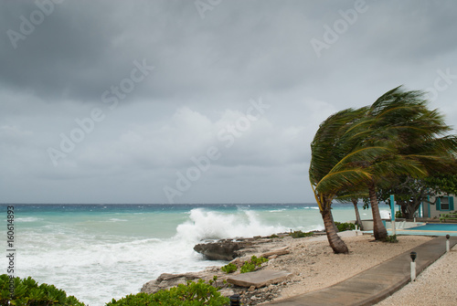 A hurricane is about to batter this caribbean beach hut. The seas are raging and the skies show the tropical storm as the power of nature is demonstrated. Waves crash on the shore photo