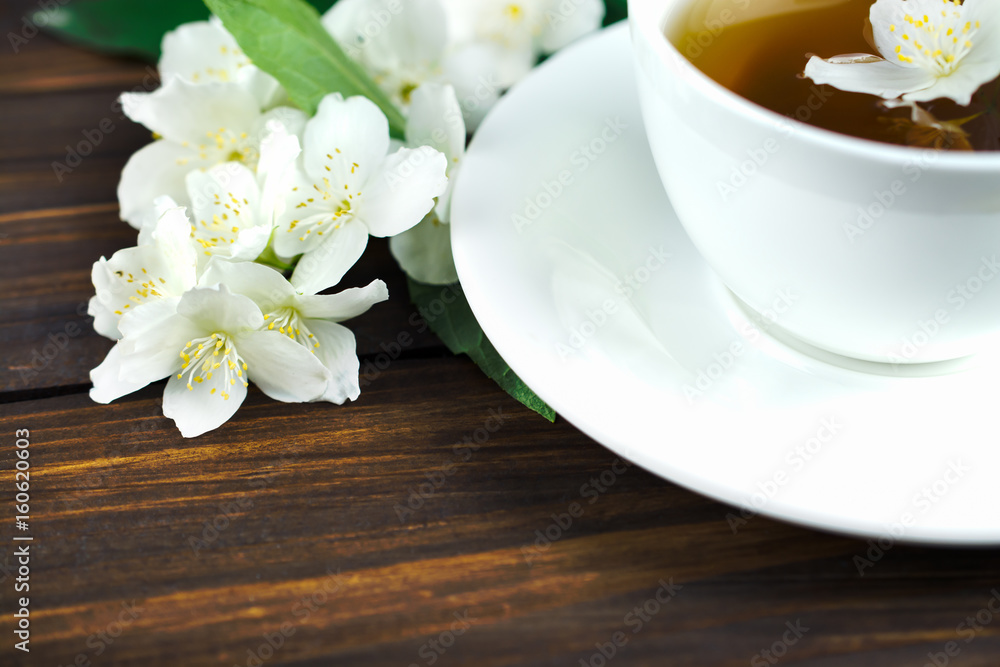 Tea with jasmine in a white cup on a wooden table.