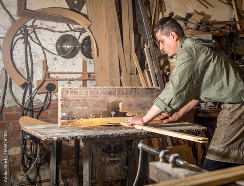 a man works on the machine with the wooden product photo