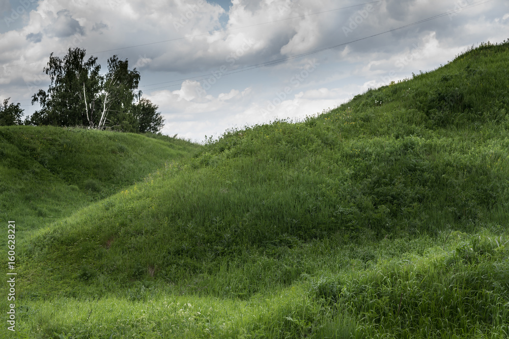 Green grass hill and blue sky with white clouds