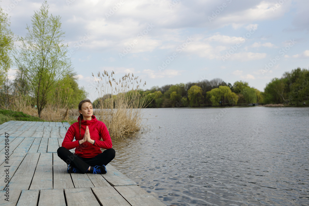 Woman meditating sitting in lotus, on near river, nature, park, natural background