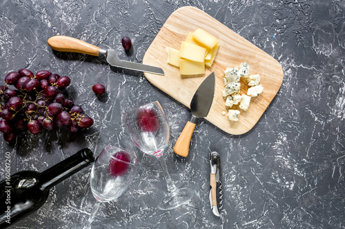 Set for drinking wine with cheese and red grape on grey stone background top view