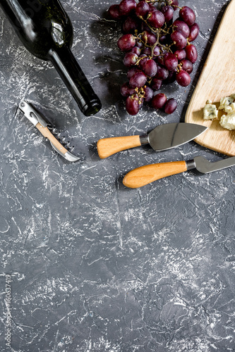 Bottle of red wine with cheese and grape aperitive on grey stone table background copyspace top view