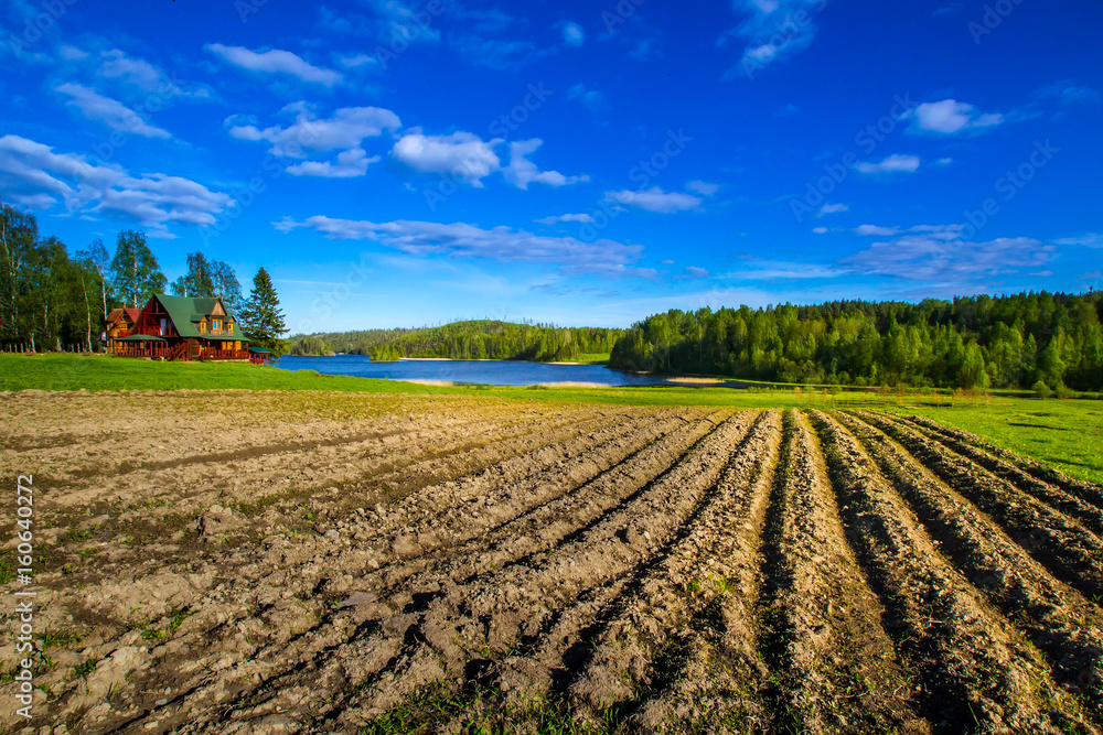 A plowed field on a farm background.