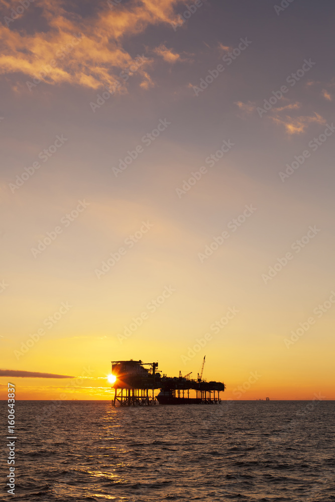 An offshore oil installation and a platform supply ship at sunset time 