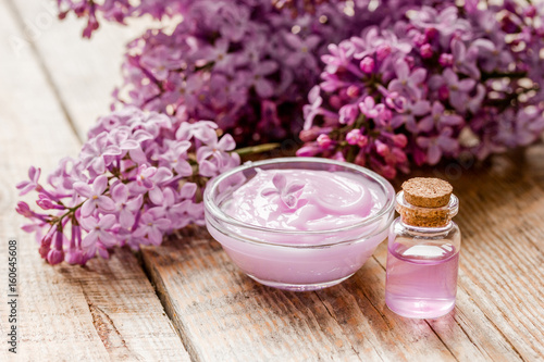 take bath with lilac cosmetic set and blossom on wooden table background