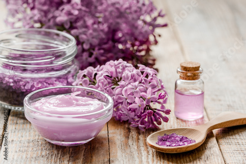 lilac cosmetics with flowers and spa set on wooden table background