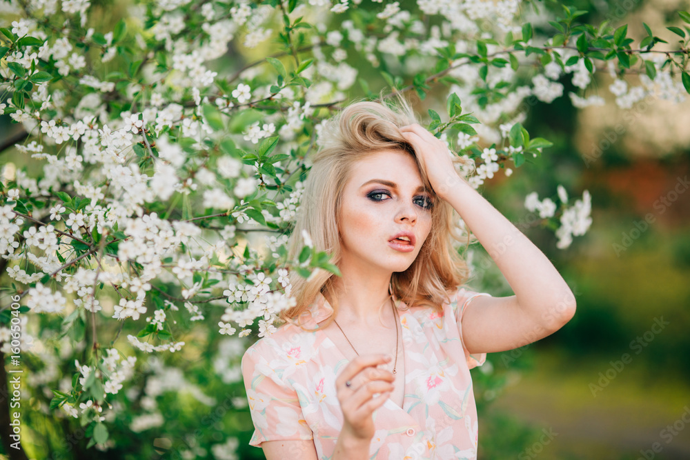 Beautiful young girl standing among the flowering trees. White flowers. Beautiful young girl standing among the flowering trees. White flowers.