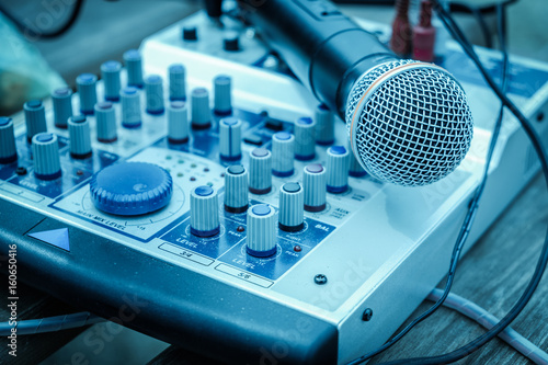 Microphone in soft focus placing on audio synthesiser electronic music instrument sound mixer machine in blur meeting room: Metallic material mic for vocal entertainment in seminar auditorium hall